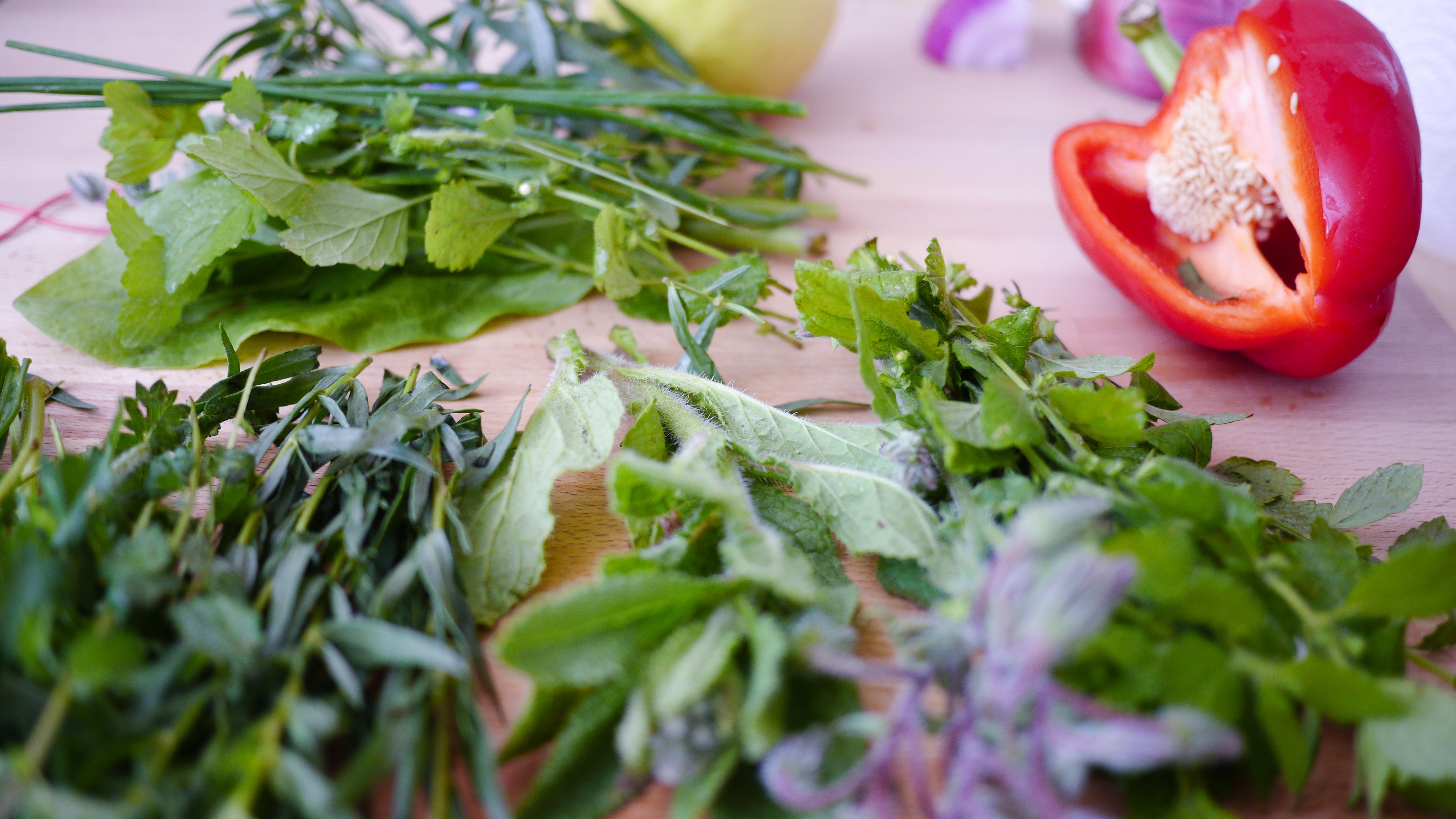 Fresh vegetables and leafy greens arranged on a wooden cutting board
